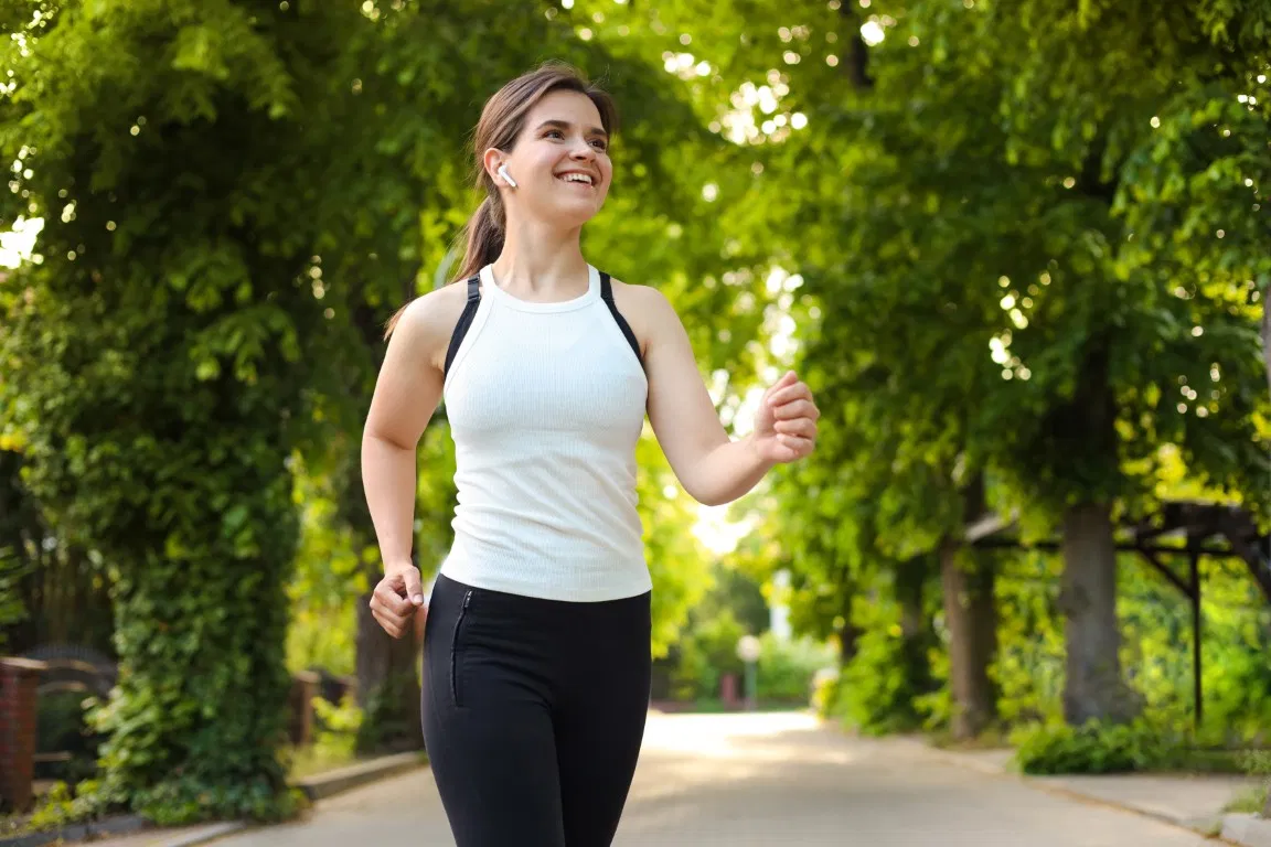 A woman runs in a park. She supports her weight management with GLP-1 medication.